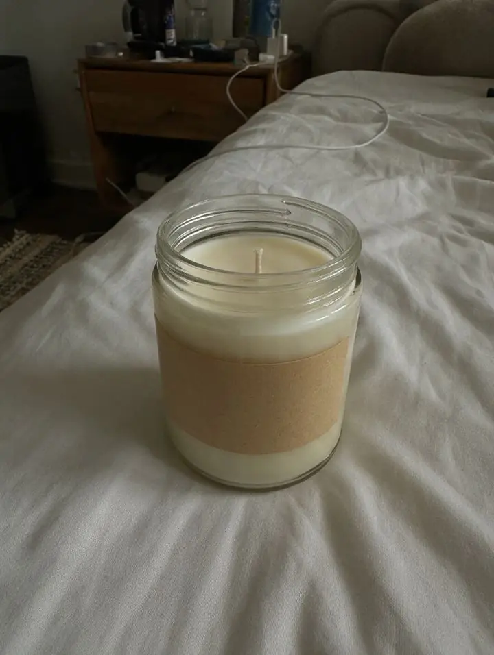 Before: phone photo of a sample candle jar on a bed